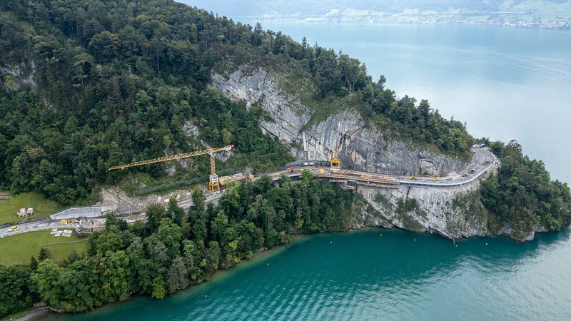 Blick aus der Vogelperspektive auf die Baustelle: Die Arbeiten verlaufen direkt zwischen steiler Felswand und Seeufer. Das ist ein eindrucksvolles Beispiel f&uuml;r pr&auml;zises Bauen unter anspruchsvollen topografischen Bedingungen.