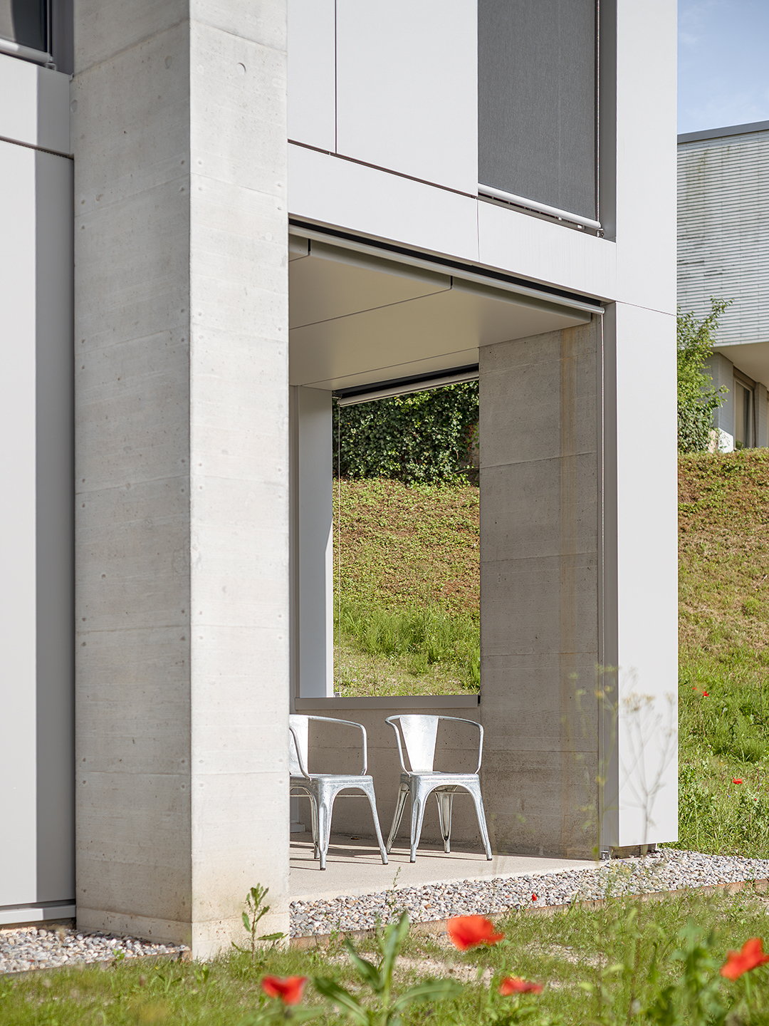Der Sitzplatz im Freien wird von der markanten Sichtbetonfassade gepr&auml;gt, die dem Haus einen klaren, reduzierten Ausdruck verleiht.